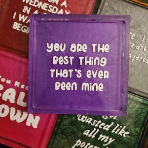 May include: Purple square coaster with white text that reads "You are the best thing that's ever been mine".