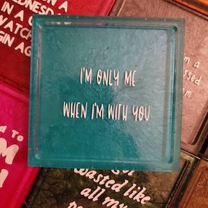 May include: A teal blue square resin coaster with white text that reads "I'm only me when I'm with you".