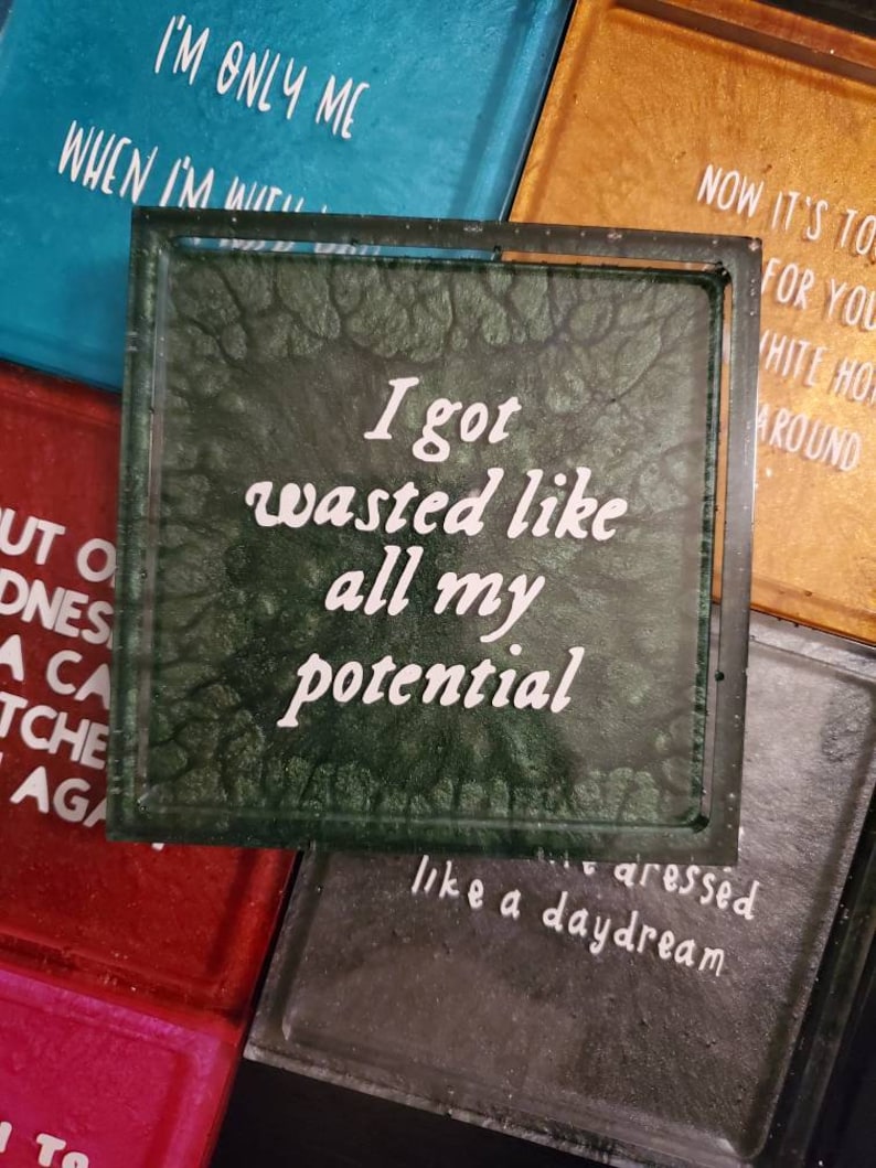 May include: A green glass coaster with white text that reads "I got wasted like all my potential like a daydream".