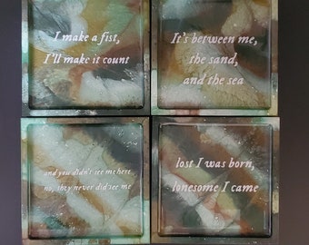 Könnte beinhalten: Vier quadratische Untersetzer mit einem grün-braun-weißen Marmormuster. Jeder Untersetzer trägt ein anderes Zitat: "I make a fist, I'll make it count", "It's between me, the sand, and the sea", "and you didn't see me here no, they never did see me", und "lost I was born, lonesome I came".