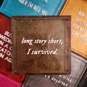 May include: A brown and green resin coaster with the text "long story short, I survived." in white lettering. The coaster has a distressed, aged look.