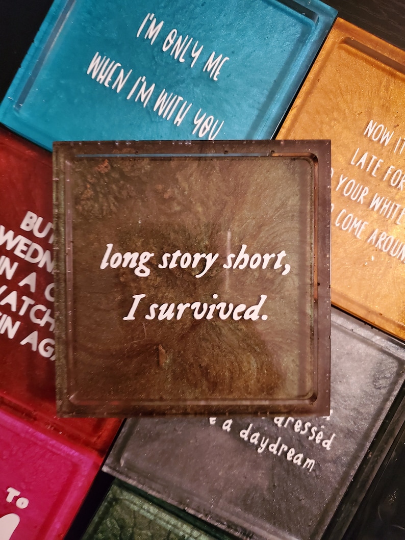 May include: A brown and green resin coaster with the text "long story short, I survived." in white lettering. The coaster has a distressed, aged look.