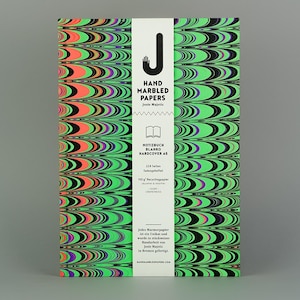 May include: A hardcover notebook with a vibrant, marbled pattern in green, black, orange, and purple. The cover features a white vertical band with the text "HAND MARBLED PAPERS" and other details. The notebook is on a gray background.
