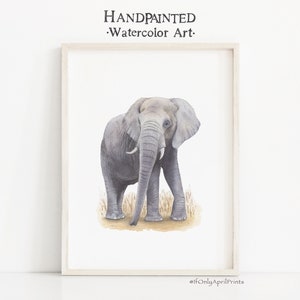 May include: A watercolor painting of a gray elephant standing in tall grass. The elephant is facing forward with its trunk lowered. The painting is framed in a white frame.