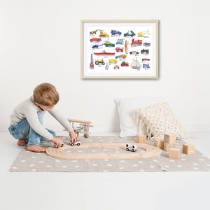 May include: A young child plays with toy cars and a wooden airplane on a gray and white rug. A framed print of a colorful illustration of various vehicles hangs on the wall behind the child.
