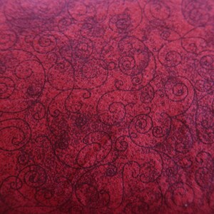 May include: Red fabric with a dark red swirl pattern.