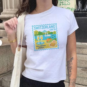 Die Schweiz Postkarten Travel Briefmarken Grafik-Baby-T-Shirt | Vintage Schweizer Alpen Reise-T-Shirt | See & Schwan Souvenir