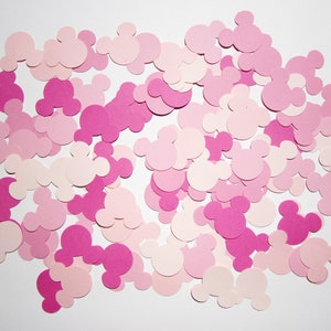 May include: A collection of pink and light pink paper cutouts in the shape of Mickey Mouse heads.