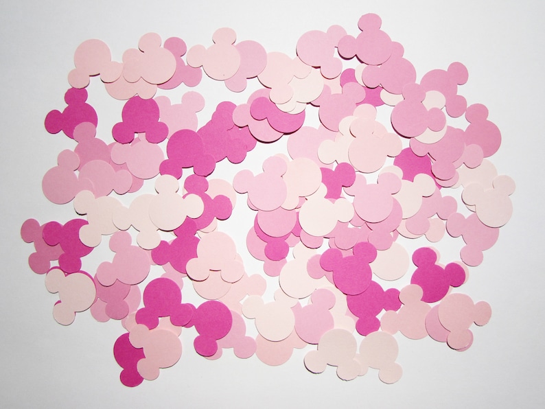 May include: A collection of pink and light pink paper cutouts in the shape of Mickey Mouse heads.