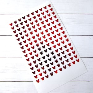 May include: A sheet of red glitter paper with a repeating pattern of Mickey Mouse heads.