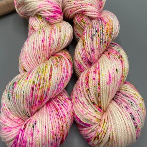 May include: Two skeins of white yarn with pink, yellow, green, and blue speckles.