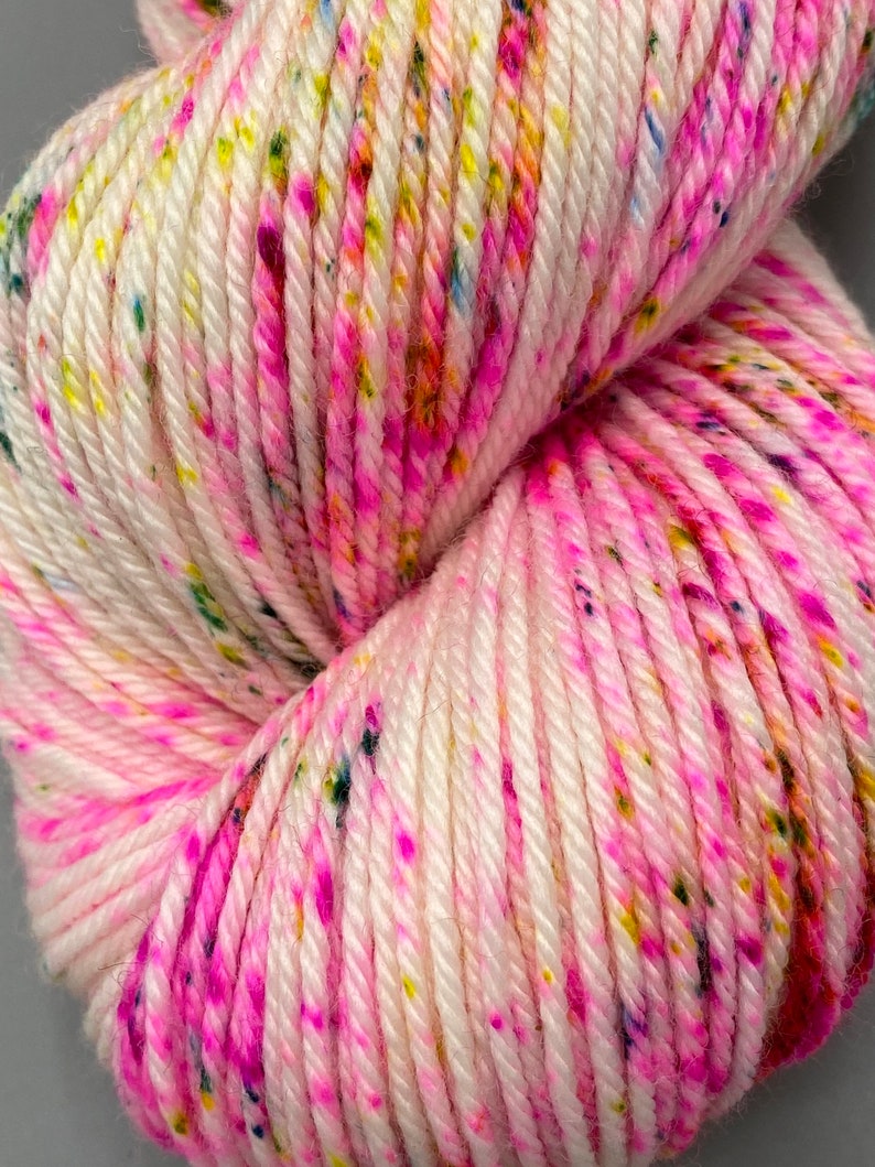 May include: White yarn with pink, yellow, and blue speckles.