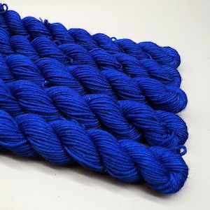 May include: A close-up of several skeins of bright blue yarn. The yarn is soft and fluffy, and it is perfect for knitting or crocheting.