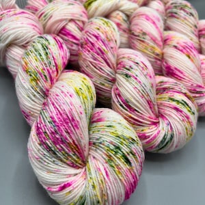 May include: A skein of white yarn with pink, green, and yellow speckles. The yarn is soft and fluffy, and it would be perfect for knitting or crocheting.