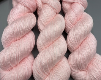 May include: Three skeins of soft, pale pink yarn. The yarn is arranged in a spiral shape.