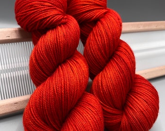 May include: Two skeins of bright orange yarn, twisted together. The yarn is soft and fluffy, perfect for knitting or crocheting.