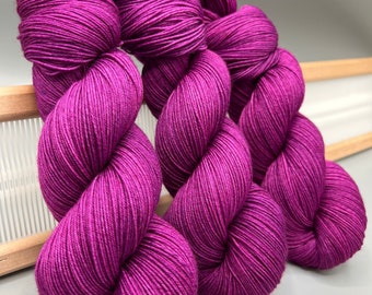 May include: Three skeins of deep purple yarn, wound into balls, ready for knitting or crocheting.