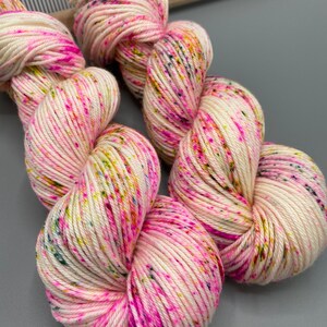 May include: Two skeins of white yarn with pink, yellow, and green speckles.