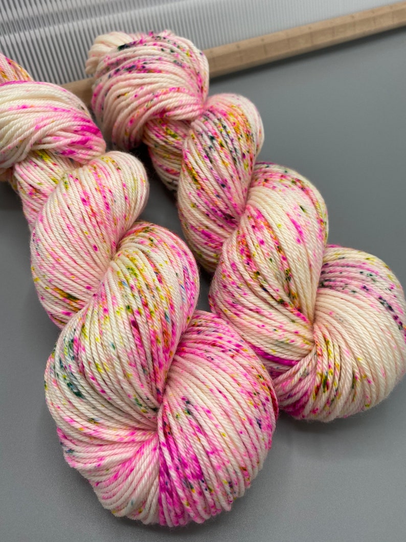May include: Two skeins of white yarn with pink, yellow, and green speckles.