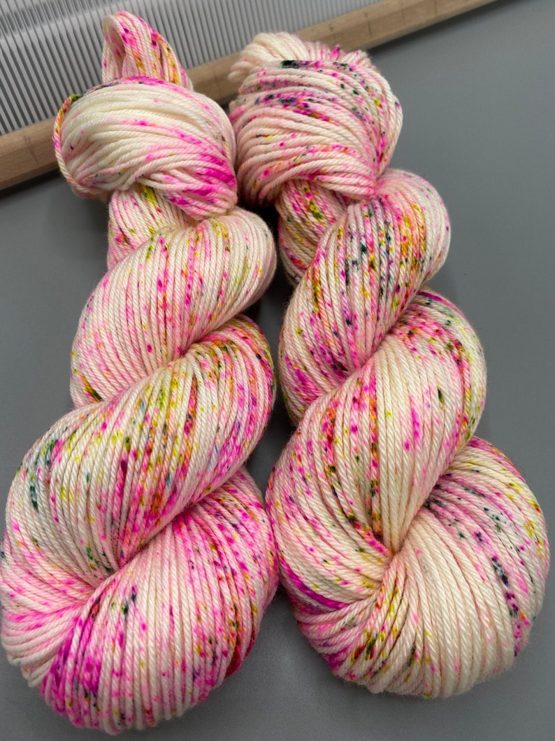 May include: Two skeins of white yarn with pink, yellow, green, and blue speckles.