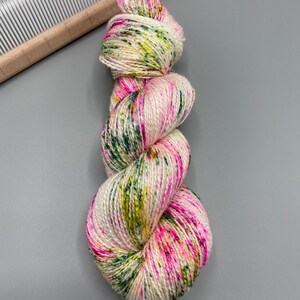 May include: A skein of yarn in a white base with speckles of pink, green, and yellow.