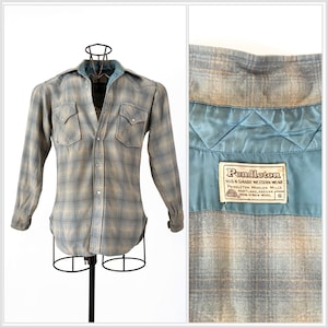 May include: A blue and tan plaid flannel shirt with a satin lining and a Pendleton label. The label reads "High Grade Western Wear, Pendleton Woolen Mills, Portland, Oregon, 100% Virgin Wool, Size S".