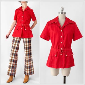 May include: A vintage red short-sleeved shirt with a matching belt and pockets, paired with plaid flared pants. The shirt has white stitching and buttons. The outfit is displayed on a mannequin and a person.
