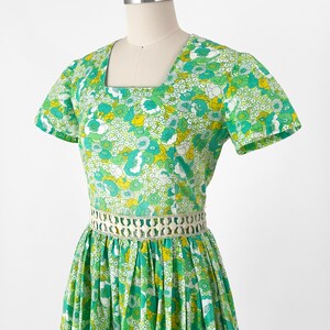 May include: A white ceramic mug with a black handle and the text "But First, Coffee" in a bold, black font. The mug is set against a blurred background, highlighting its clean design.