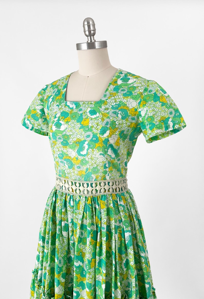 May include: A white ceramic mug with a black handle and the text "But First, Coffee" in a bold, black font. The mug is set against a blurred background, highlighting its clean design.