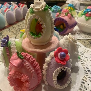 May include: A collection of decorated Easter eggs, each with a unique design and color. The eggs are made of sugar and decorated with intricate details, including flowers, birds, and other spring motifs.