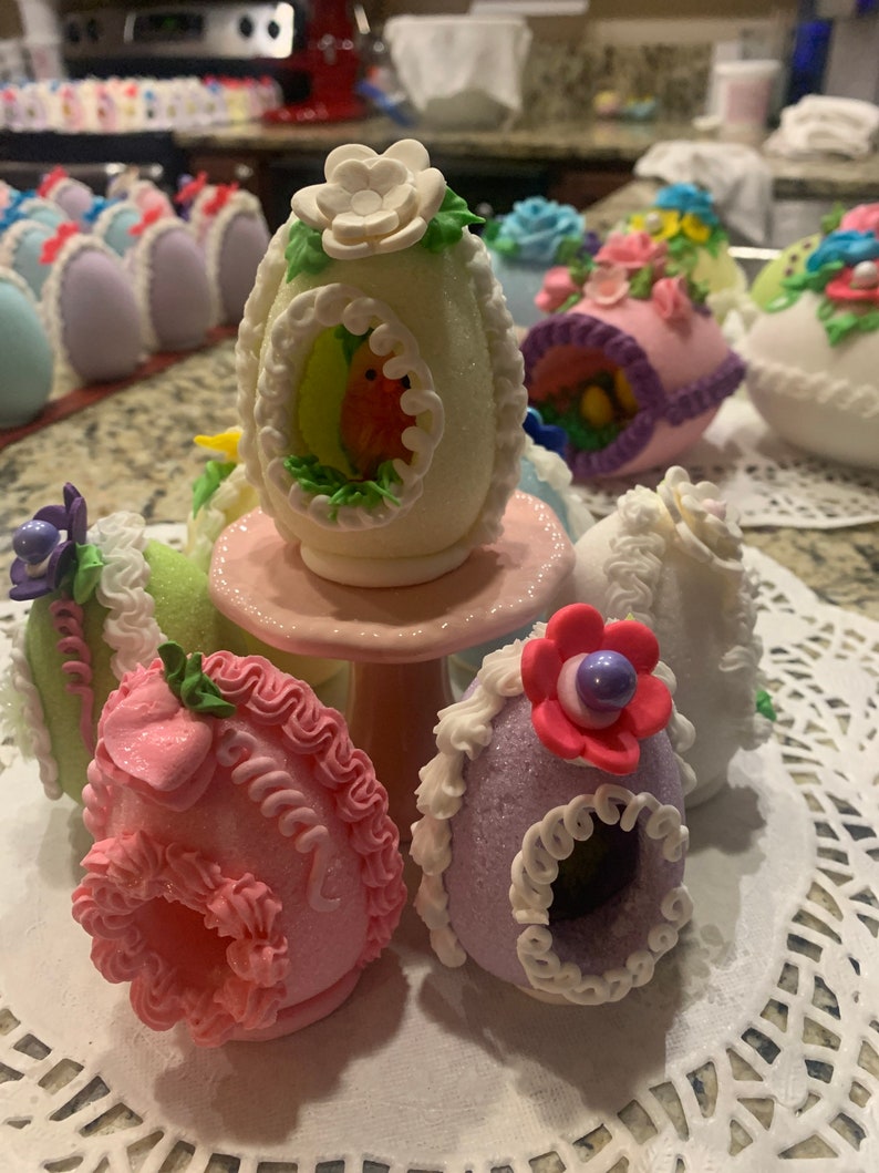 May include: A collection of decorated Easter eggs, each with a unique design and color. The eggs are made of sugar and decorated with intricate details, including flowers, birds, and other spring motifs.