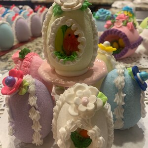 May include: A collection of decorated Easter eggs. The eggs are white, purple, and blue with various pastel-colored decorations, including flowers, birds, and nests.