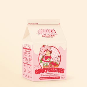 May include: A pink and white cardboard box containing a Strawberry Shortcake scented candle. The box features a cartoon image of Strawberry Shortcake and her cat, Berry Besty. The text on the box reads "Berry Besties The World of Strawberry Shortcake Strawberry Shortcake Scented Candle".
