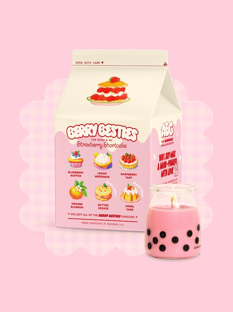 May include: A pink and black milk carton-shaped candle with a strawberry shortcake design. The candle is labelled "Berry Besties" and features different flavours of shortcake, including blueberry muffin, lemon meringue, raspberry tart, orange blossom, butter cookie, and angel cake. The candle is made with 100% soy wax and is hand-poured with love.