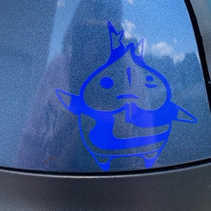 May include: A blue vinyl sticker of a cartoon character with a crown on its head. The character has a round body and large eyes. The sticker is on a blue car.