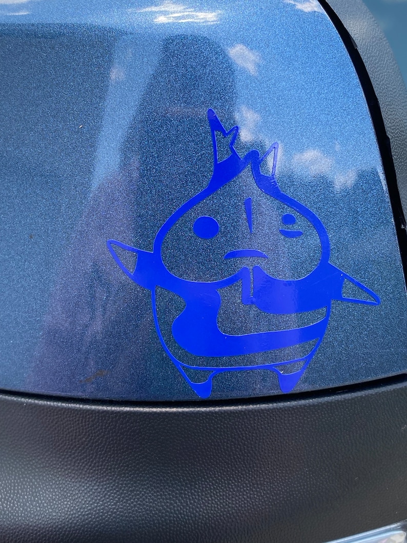 May include: A blue vinyl sticker of a cartoon character with a crown on its head. The character has a round body and large eyes. The sticker is on a blue car.