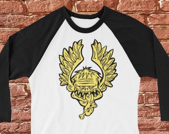 Peut inclure: Un t-shirt de baseball blanc et noir avec un motif jaune d'un monstre ailé avec la langue qui sort.