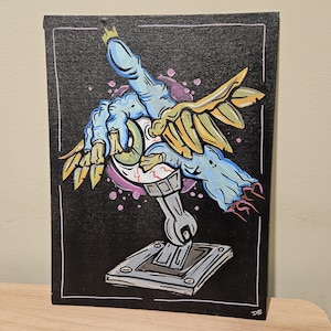 May include: A hand-painted canvas art piece featuring a surreal design. The artwork depicts a blue hand with a crown, holding an eye and a wrench. The background is black with colorful accents, and the piece is framed in white.