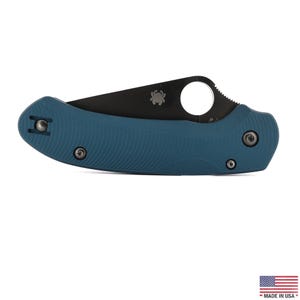 Op de afbeelding: Een inklapbaar zakmes met een matblauw getextureerd handvat en een zwart lemmet. Het lemmet heeft een rond duimgat en een klein spinnenlogo. Het handvat is bevestigd met zilverkleurige schroeven en bevat een metalen clip voor aan de broekzak.