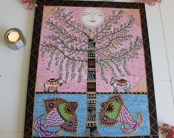 Puede incluir: Un cuadro rectangular sobre lienzo que presenta un árbol central con un rostro solar estilizado encima. El fondo es rosa con patrones en espiral. Dos vacas se sitúan sobre una línea de horizonte encima de agua azul con dos peces.