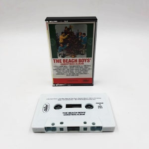 May include: A white cassette tape with a black label. The label has the text "The Beach Boys' Christmas Album" and the number "164".