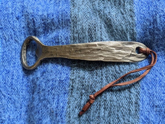 58 favorites and a groomsmen angle give this forged opener a proven gifting identity — clearly resonates as a memorable keepsake.