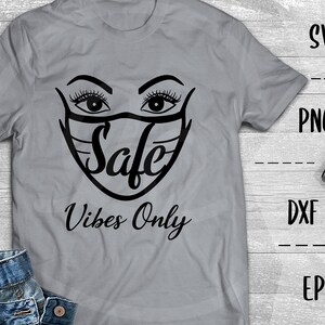 Puede incluir: Una camiseta gris con un gráfico negro de una cara con una máscara con la palabra "Safe" dentro. El texto "Vibes Only" está debajo del gráfico.