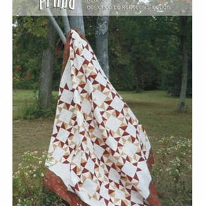 May include: A quilt pattern called "Prima" designed by Ruby Blue Quilting Studio. The quilt is made with white, brown, and red fabric and features a star pattern.