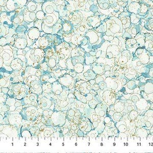 May include: A fabric with a repeating pattern of blue and gold circles on a white background. The circles vary in size and overlap, creating a textured appearance. A ruler is at the bottom, showing measurements in inches.