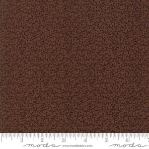 May include: Brown fabric with a repeating pattern of dark brown vines and small leaves. The fabric has a ruler along the bottom edge, with the word "moda" printed on it.