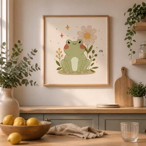 May include: A framed art print featuring a cartoon frog with a daisy and floral accents. The frog is green with a cream-colored belly and rosy cheeks. The artwork is set against a cream background with a wooden frame, suitable for a nursery or children's room.