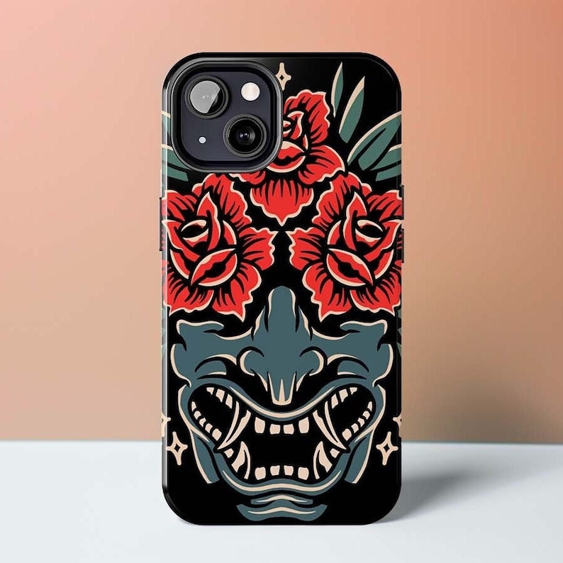 May include: Black phone case with a red and green illustration of a Japanese demon face with roses around it.