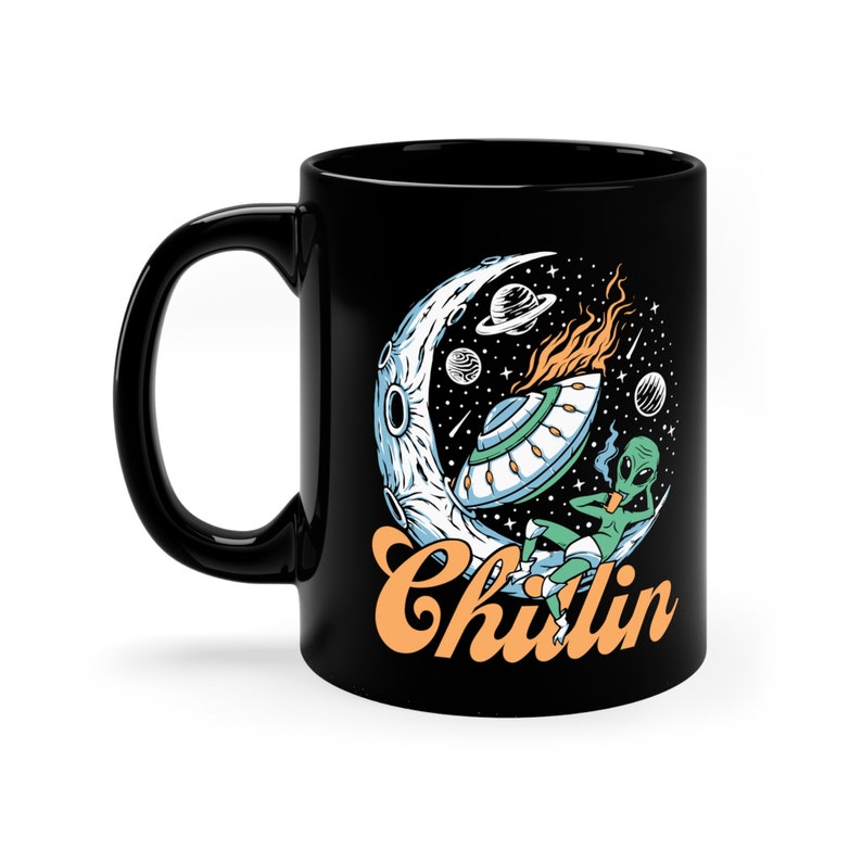 May include: Black coffee mug featuring a graphic of an alien relaxing on a crescent moon with a UFO and the text "Chillin".