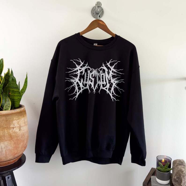 May include: Black sweatshirt with a white graphic print of the word "CUSTOM" in a metal band style font.